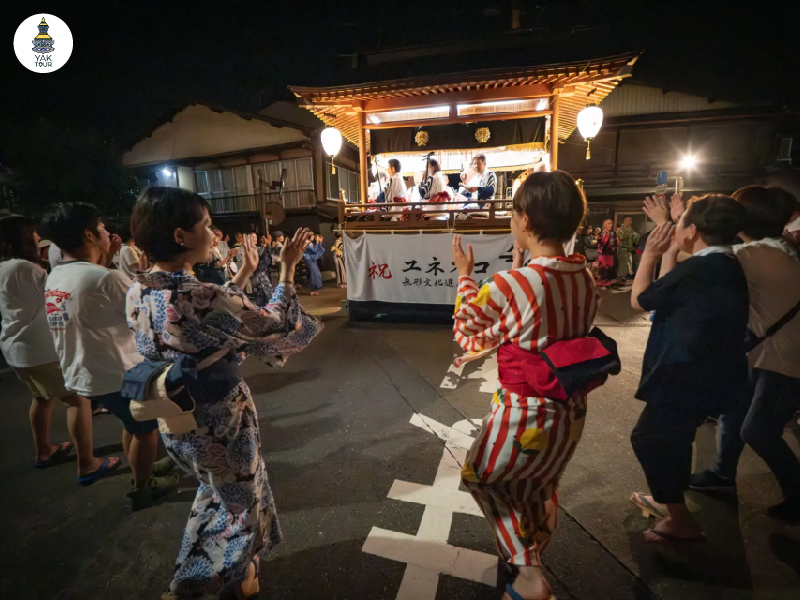 ผู้คนในชุดยูกาตะร่วมเต้นรำในเทศกาล Gujo Odori ท่ามกลางบรรยากาศค่ำคืนและแสงโคมไฟ